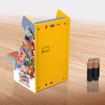 Yellow retro handheld arcade console with Street Fighter II artwork and Capcom logo on a wooden surface, with batteries nearby.